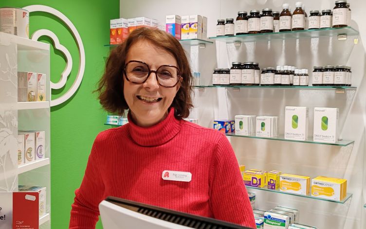 A woman standing in front of a medicine shelf.