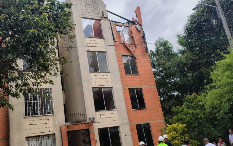 Ein zerstörtes Wohnhaus, vor dem Einsatzkräfte und Helfende stehen.  
