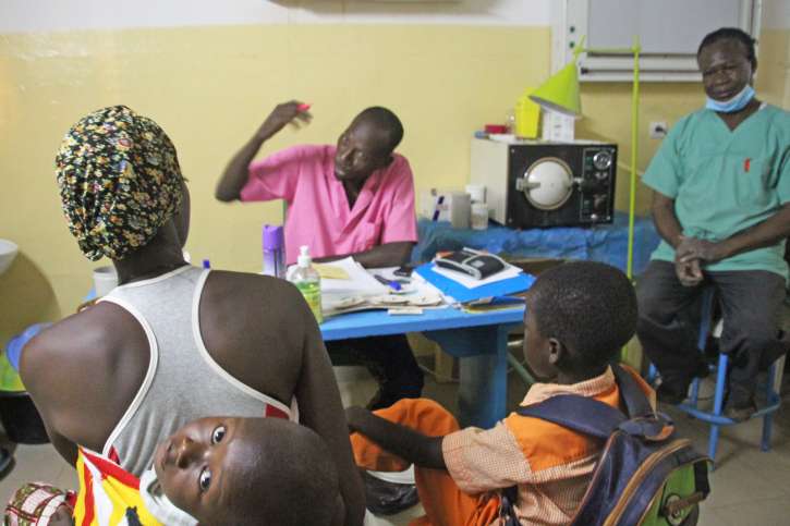 Krankenpfleger Joseph Sébé berät eine Mutter mit ihren Kindern in der Gesundheitsstation von A.M.P.O. in Burkina Faso.
