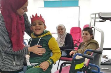 Zufriedene Gesichter nach einer erfolgreich abgeschlossenen praktischen Einheit: Lina Ghamam, Physiotherapeutin der Al Hussein Society, mit dem kleinen Patienten Jousef 