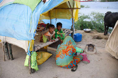 Zwei Kinder mit ihrer Mutter in einem Zelt.