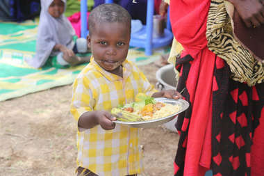 Kind in Somalia hält einen Teller mit Essen in der Hand