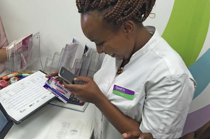 Eine Apothekenmitarbeiterin in Kenia liest mit einem Smartphone den Sicherheitscode ab.