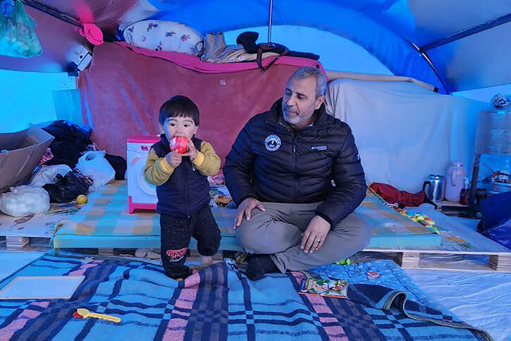 Ein Kind befindet sich mit einem Helfer in einem provisorischen Zelt