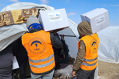 Helfende von IBC verteilen Hilfsgüter in einem syrischen Lager